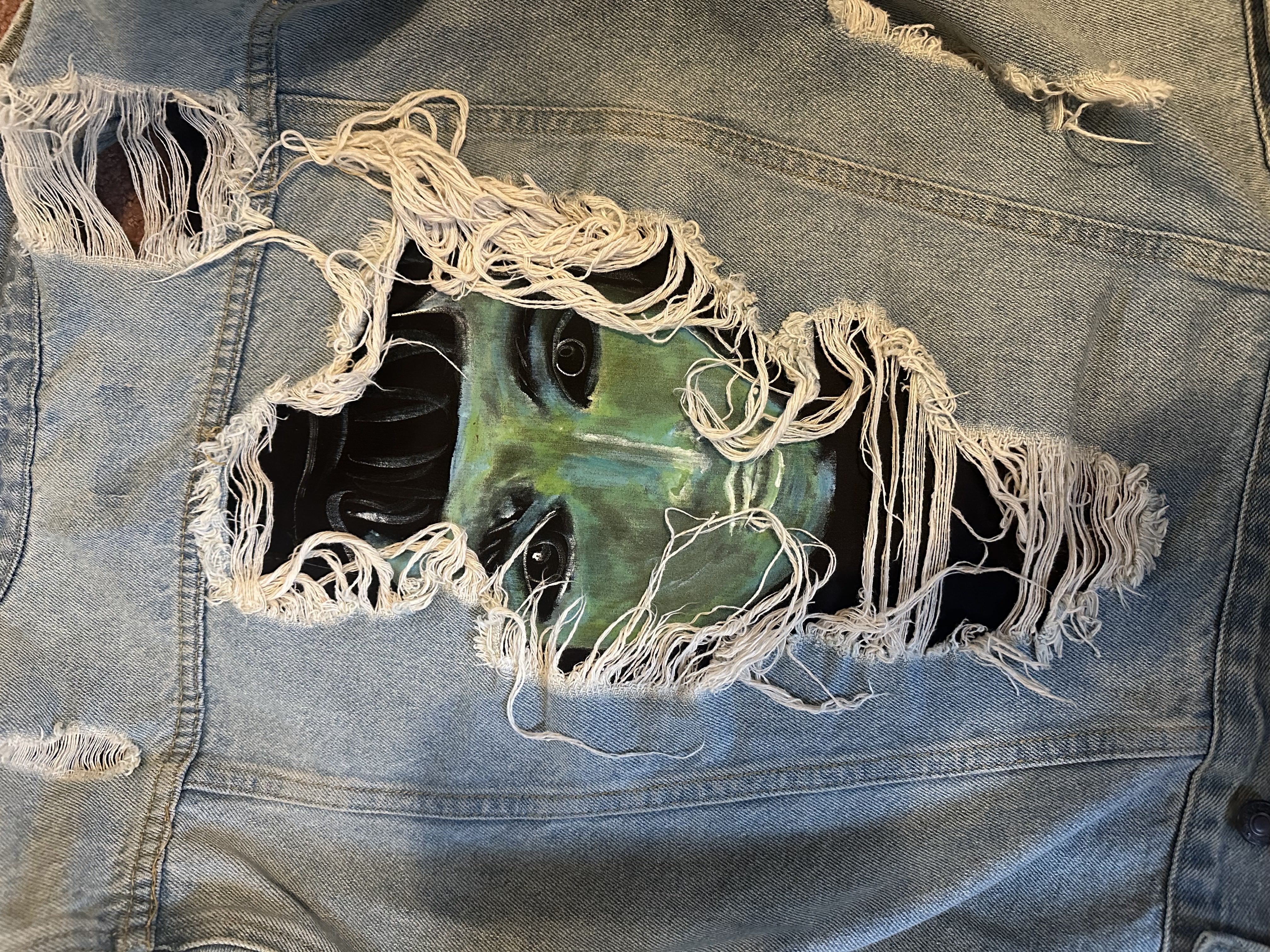 Painted denim jacket — face portrait through torn fabric