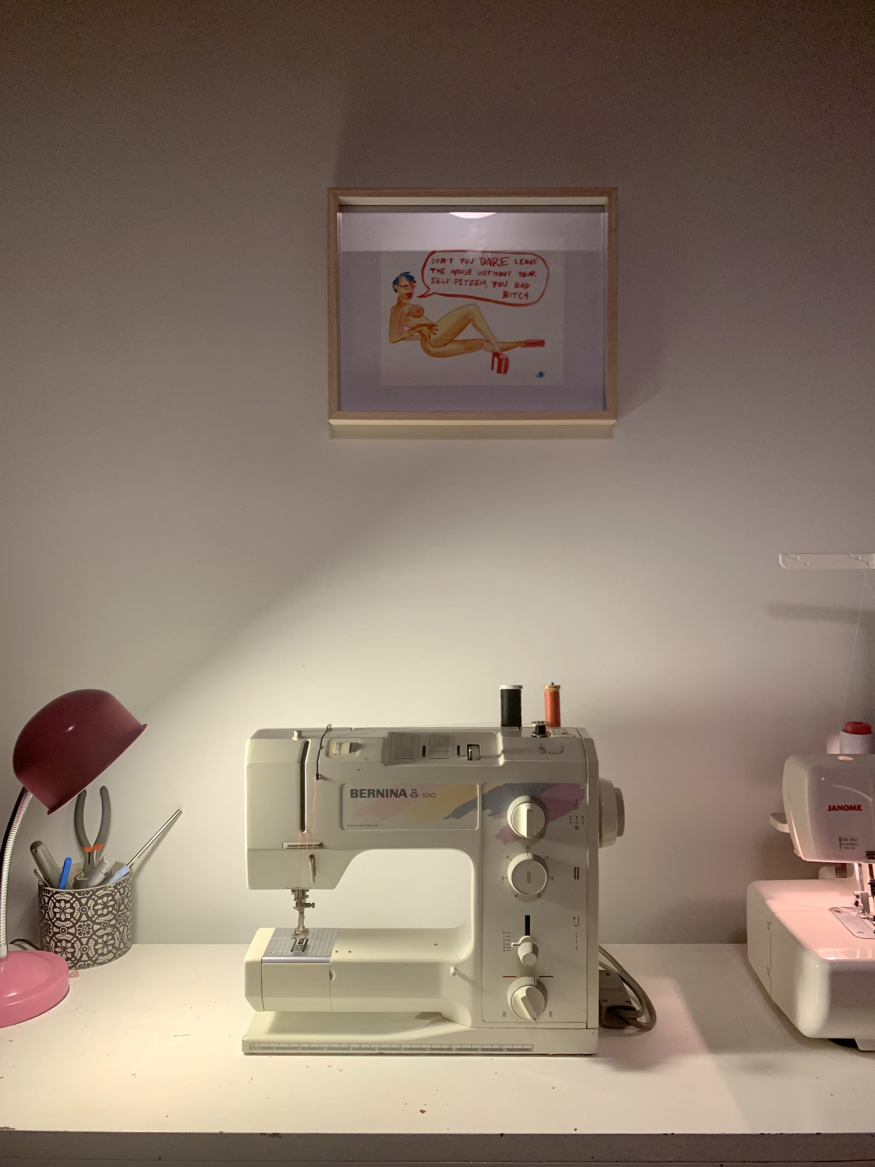 Erica Bowe's sewing room, with a Bernina 1010 machine at a work desk beneath a framed print