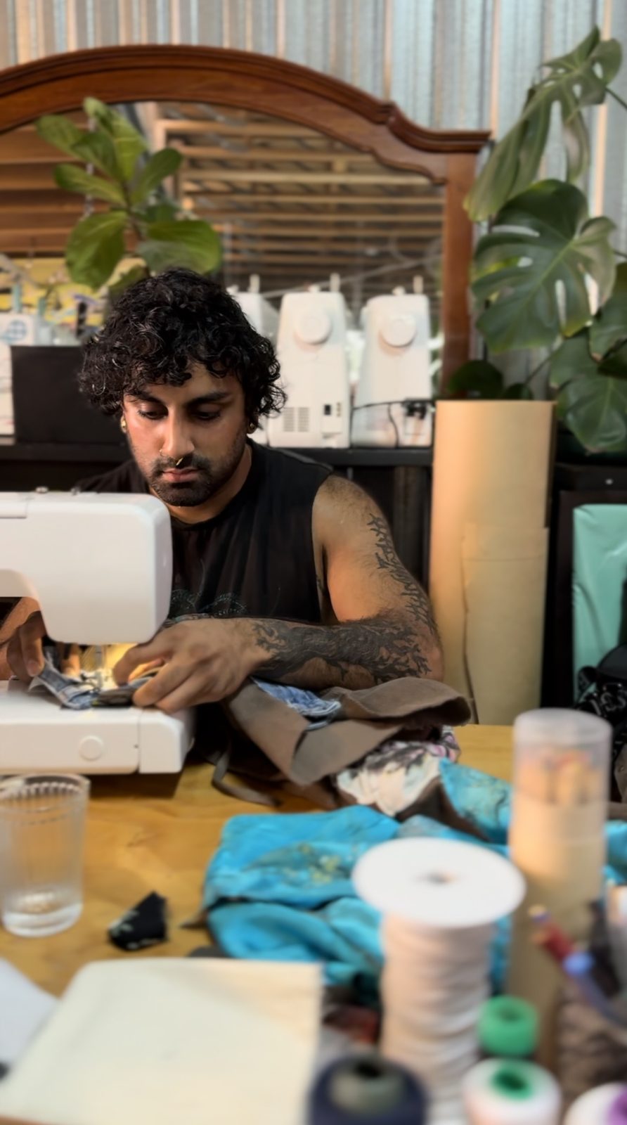 Participant sewing at a machine surrounded by plants