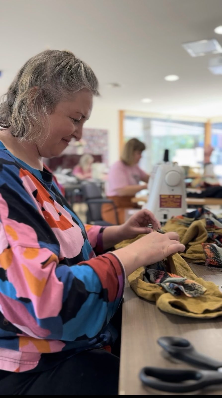 Participant smiling while hand stitching fabric